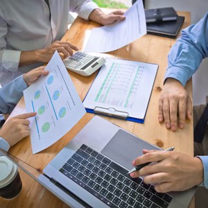 Business professionals reviewing investment reports and financial data at a meeting.