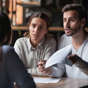 Concerned investors discussing legal rights with an attorney over financial documents.