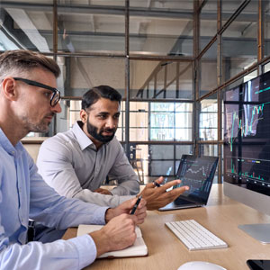 Two businessmen analyzing financial charts on a computer.